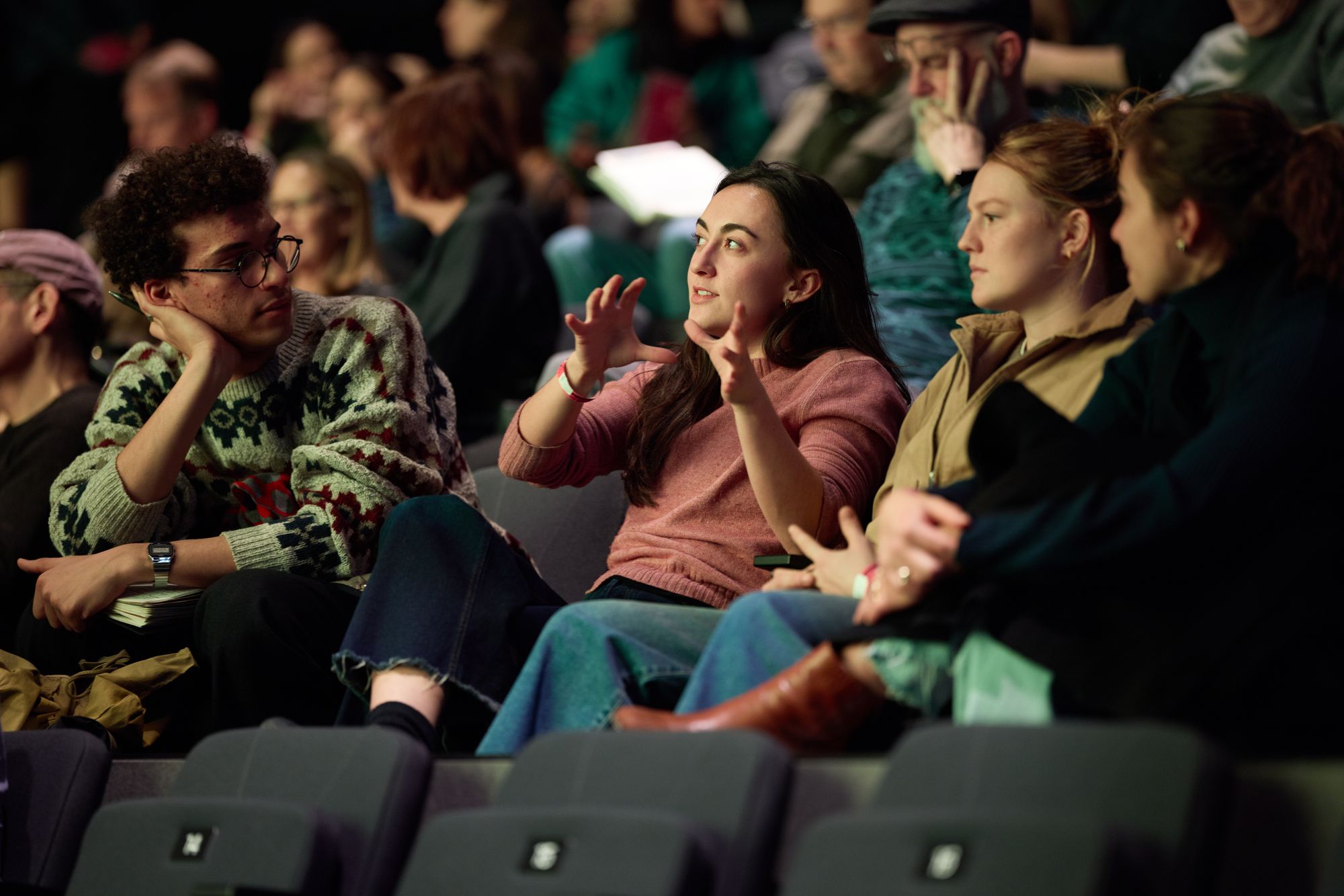 A screening attendee talks to friends, gesturing thoughtfully.